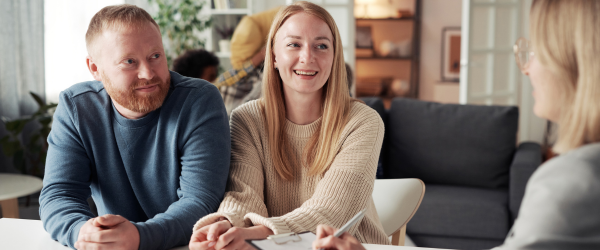 Two prospective foster parents sitting at a coffee table